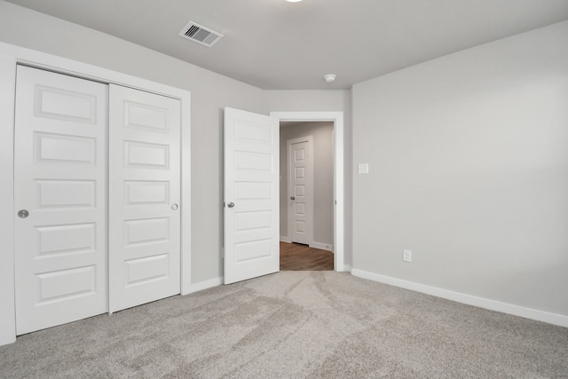 unfurnished bedroom with light colored carpet and a closet