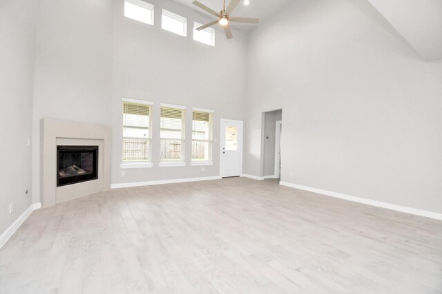 unfurnished living room with ceiling fan, high vaulted ceiling, and light hardwood / wood-style floors