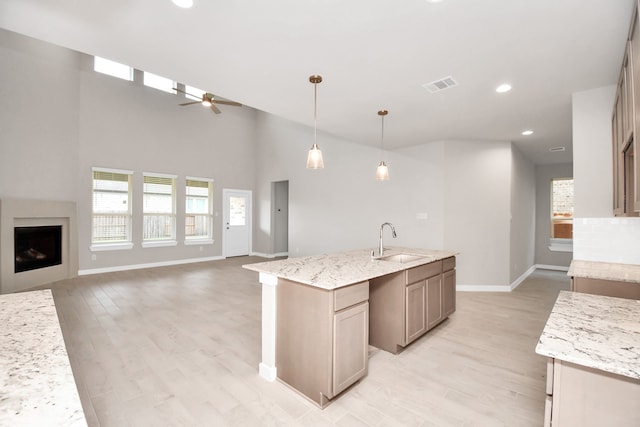 kitchen with ceiling fan, light stone countertops, pendant lighting, and sink