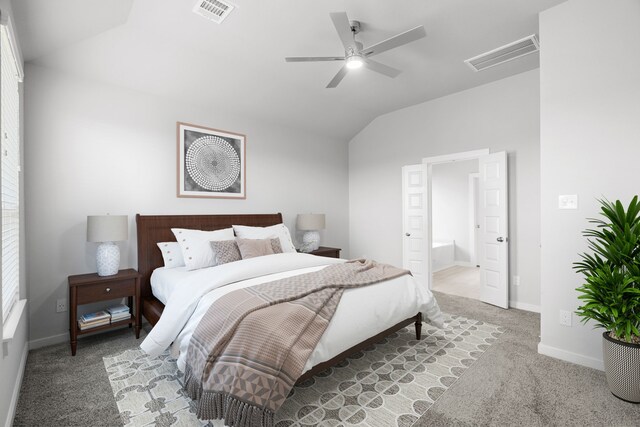 bedroom featuring ceiling fan, ensuite bathroom, light carpet, and vaulted ceiling