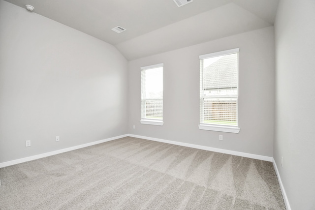 carpeted empty room featuring vaulted ceiling