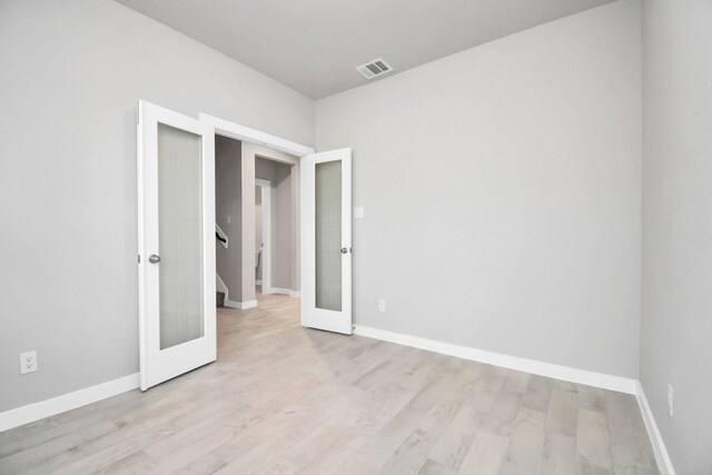 unfurnished bedroom with french doors and light hardwood / wood-style floors