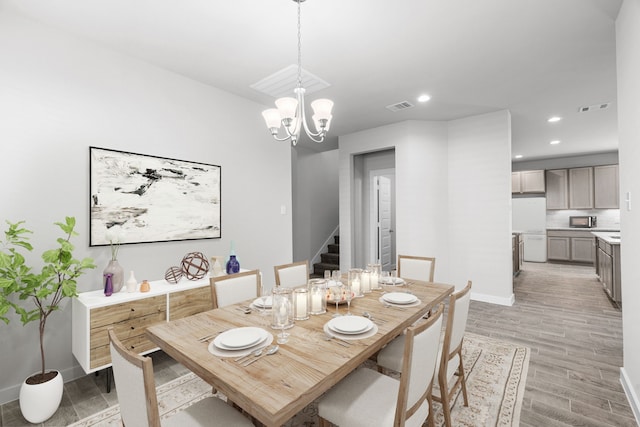 dining room with light wood-type flooring and an inviting chandelier