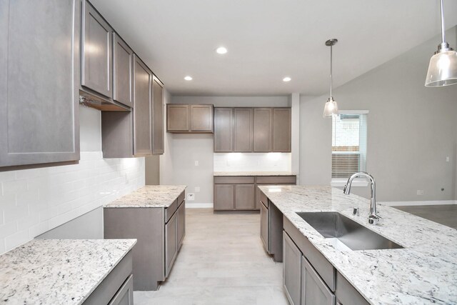 kitchen with light stone counters, sink, and decorative light fixtures