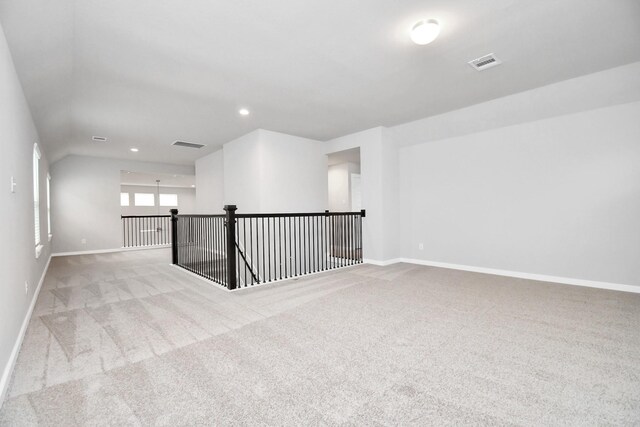 carpeted spare room with vaulted ceiling