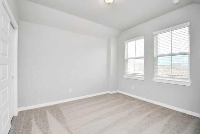 spare room featuring vaulted ceiling and carpet