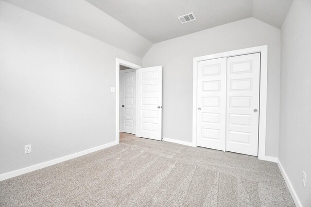 unfurnished bedroom with lofted ceiling, light colored carpet, and a closet