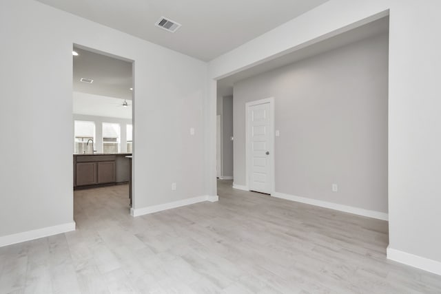 unfurnished room featuring ceiling fan, light hardwood / wood-style floors, and sink