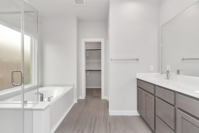 8447 Northern Pintail Dr, Houston, TX 77049 - bathroom with a spacious closet, a shower stall, a bath, double vanity, and baseboards