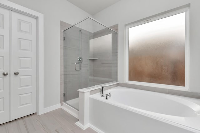 8447 Northern Pintail Dr, Houston, TX 77049 - bathroom with a stall shower, a bath, and baseboards