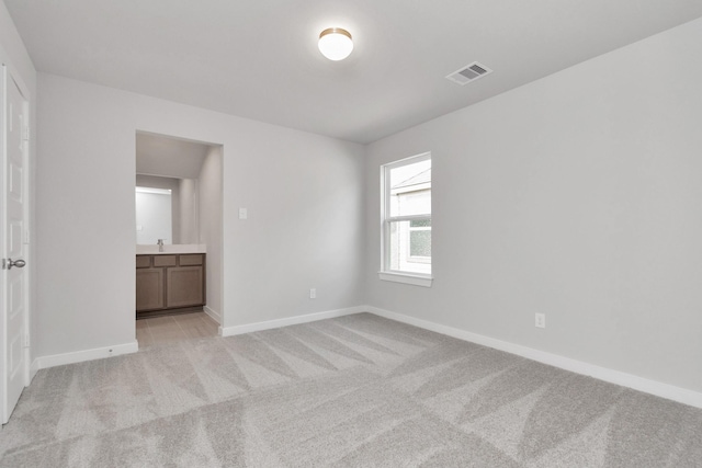 8447 Northern Pintail Dr, Houston, TX 77049 - unfurnished bedroom with light colored carpet, baseboards, ensuite bathroom, and a sink