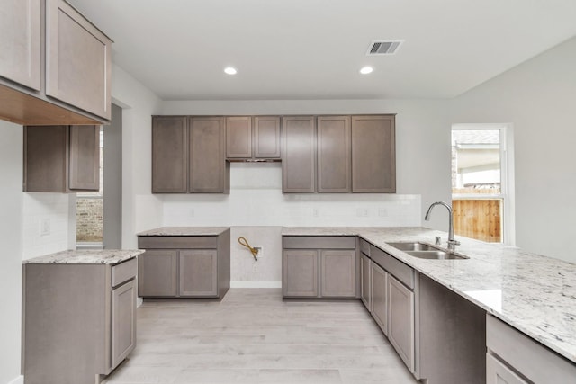8447 Northern Pintail Dr, Houston, TX 77049 - kitchen with a sink, light stone countertops, light wood-style floors, decorative backsplash, and recessed lighting