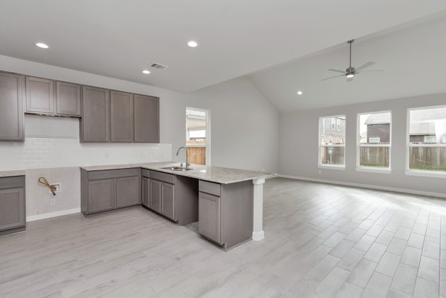 kitchen featuring plenty of natural light, kitchen peninsula, ceiling fan, and vaulted ceiling