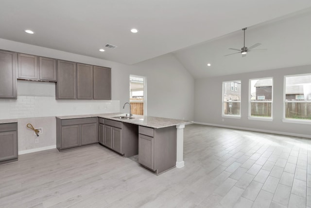 8447 Northern Pintail Dr, Houston, TX 77049 - kitchen featuring a peninsula, lofted ceiling, a sink, a ceiling fan, and decorative backsplash