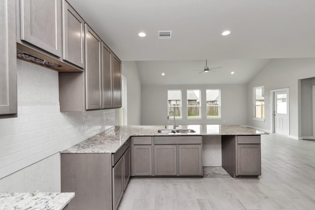 8447 Northern Pintail Dr, Houston, TX 77049 - kitchen featuring a sink, a peninsula, vaulted ceiling, light stone countertops, and a ceiling fan