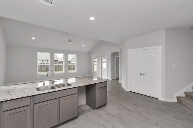 8447 Northern Pintail Dr, Houston, TX 77049 - kitchen featuring a sink, a ceiling fan, lofted ceiling, light stone counters, and light wood-style floors