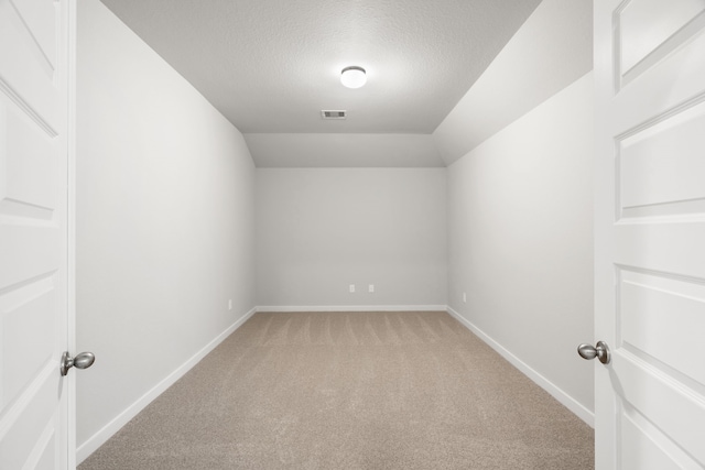 interior space featuring lofted ceiling, light carpet, and a textured ceiling