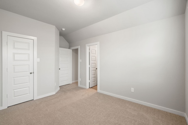 unfurnished bedroom featuring light colored carpet and vaulted ceiling