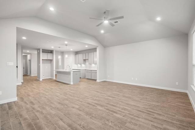 unfurnished living room featuring lofted ceiling, light hardwood / wood-style flooring, and ceiling fan