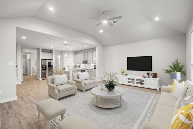 living room with lofted ceiling, ceiling fan, light hardwood / wood-style floors, and sink