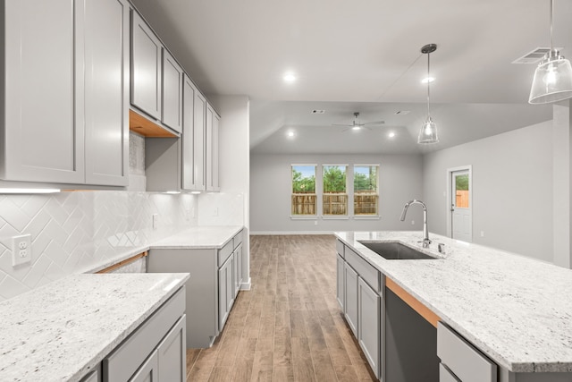 kitchen featuring a center island with sink, sink, light wood-type flooring, and gray cabinetry