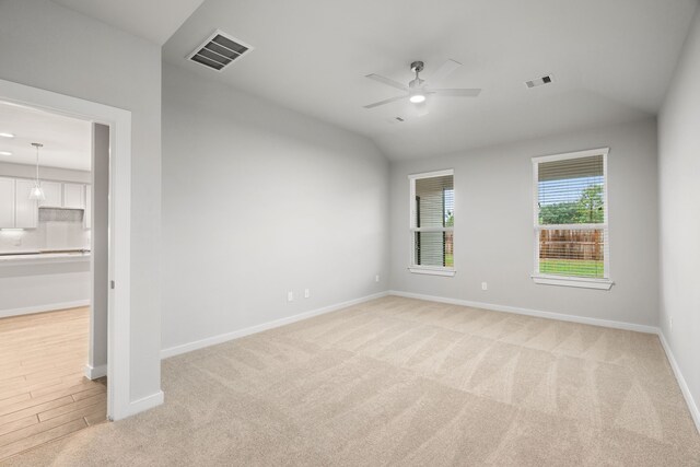 unfurnished room featuring lofted ceiling, ceiling fan, and light colored carpet