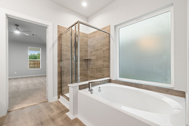 bathroom with plus walk in shower, ceiling fan, and wood-type flooring