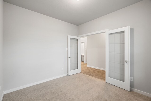 unfurnished bedroom featuring light colored carpet and french doors