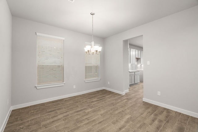 unfurnished dining area with light wood-type flooring and a notable chandelier