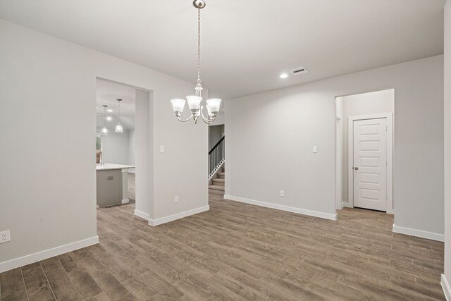 unfurnished dining area with hardwood / wood-style floors and an inviting chandelier