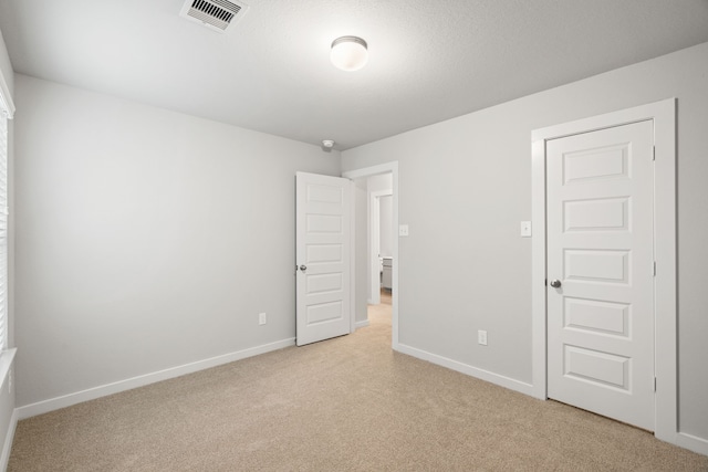 unfurnished bedroom with a closet and light carpet