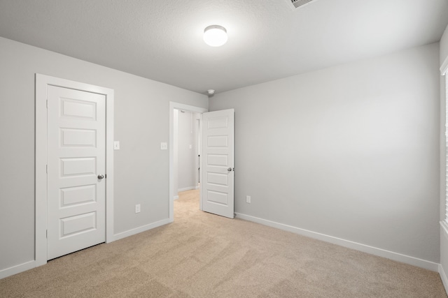 unfurnished bedroom with light carpet, a textured ceiling, and a closet