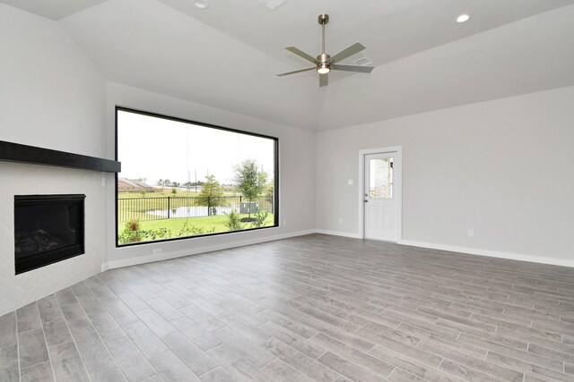 unfurnished living room with light hardwood / wood-style flooring, ceiling fan, and high vaulted ceiling