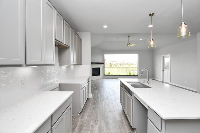 kitchen with gray cabinets, an island with sink, sink, and ceiling fan