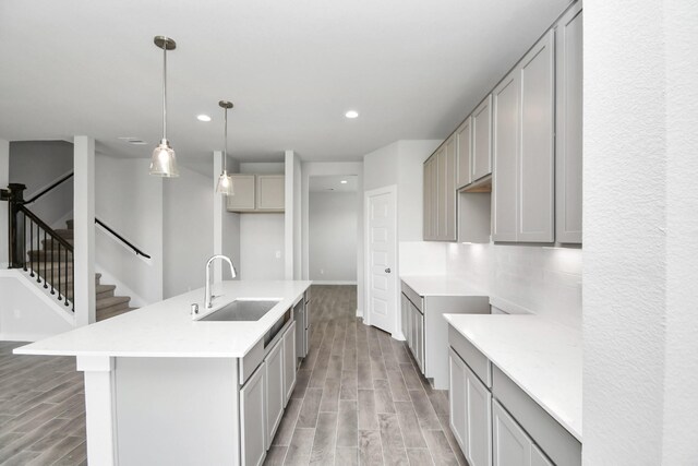 kitchen featuring gray cabinets, decorative light fixtures, an island with sink, sink, and light hardwood / wood-style floors