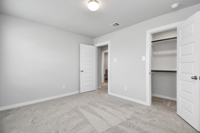 unfurnished bedroom featuring a closet and light colored carpet