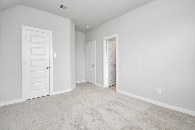 unfurnished bedroom with lofted ceiling and light carpet