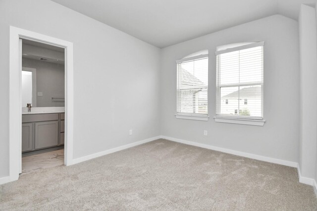 carpeted empty room featuring sink and vaulted ceiling