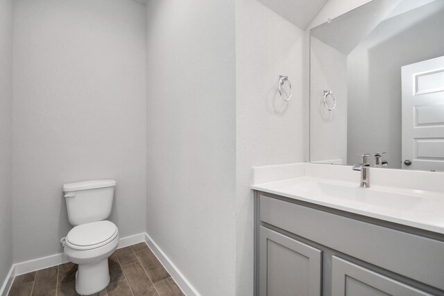 bathroom with lofted ceiling, vanity, toilet, and hardwood / wood-style floors