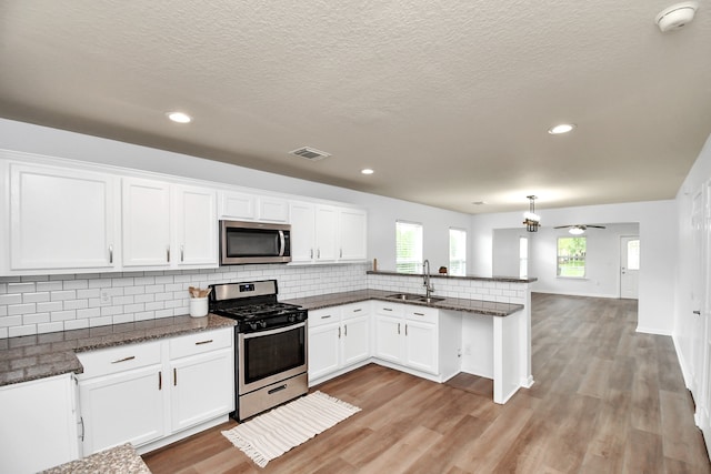 kitchen featuring appliances with stainless steel finishes, light hardwood / wood-style flooring, kitchen peninsula, and sink