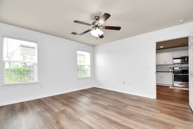 empty room with a healthy amount of sunlight, ceiling fan, and wood-type flooring