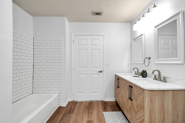 bathroom with tiled shower / bath, vanity, and hardwood / wood-style floors