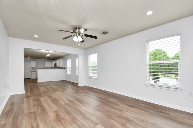 unfurnished living room featuring hardwood / wood-style floors, ceiling fan, and plenty of natural light