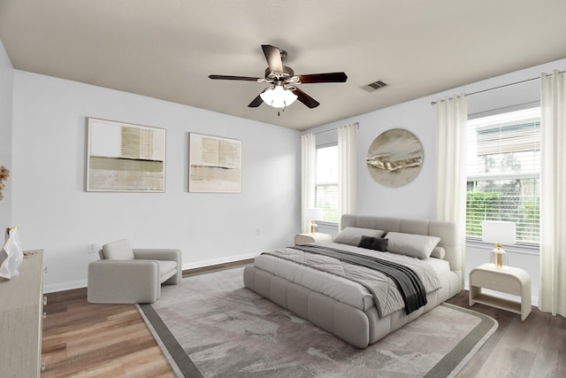 bedroom with multiple windows, hardwood / wood-style flooring, and ceiling fan