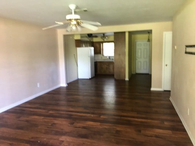 unfurnished living room featuring ceiling fan and dark hardwood / wood-style floors