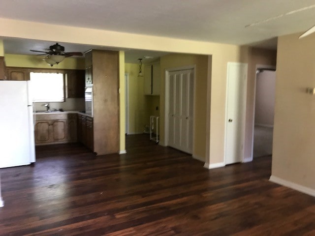 unfurnished living room featuring ceiling fan, sink, and dark hardwood / wood-style flooring