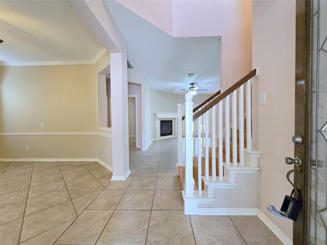 foyer with crown molding, light tile patterned floors, and ceiling fan