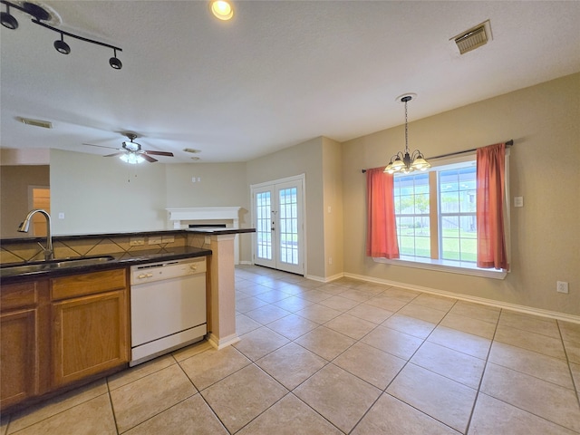 kitchen with sink, ceiling fan with notable chandelier, white dishwasher, pendant lighting, and light tile patterned floors