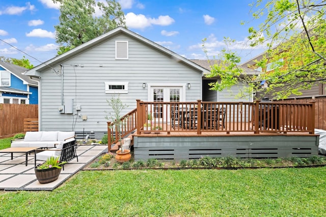 back of property featuring a wooden deck, a patio, an outdoor living space, and a yard