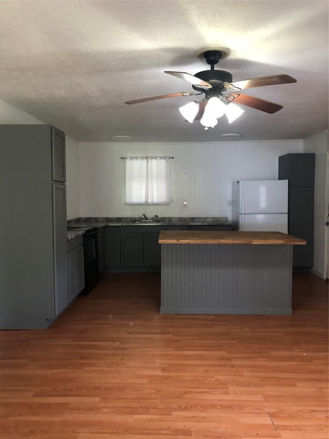 kitchen featuring white fridge, black electric range oven, stainless steel fridge, and light wood-type flooring